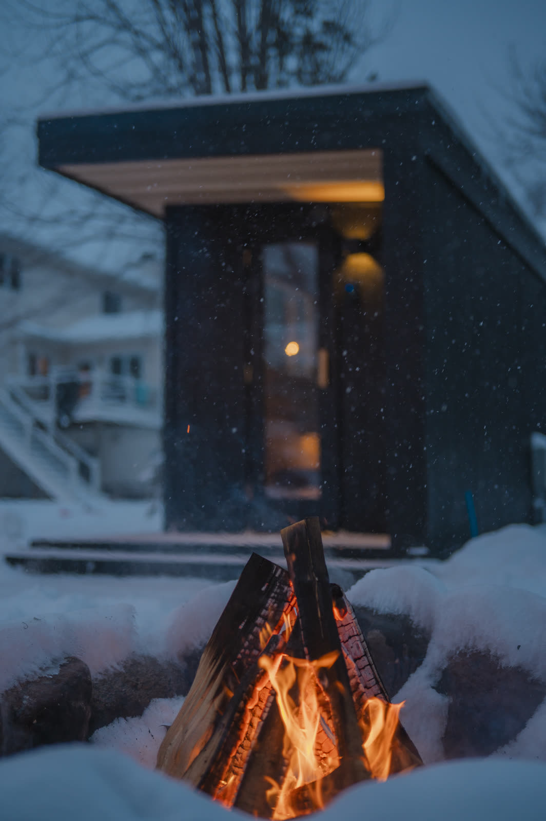 A fire pit in the foreground, the sauna glowing behind