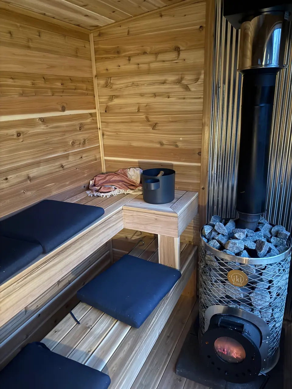 Clear cedar paneling and benches next to a wood-fired stove