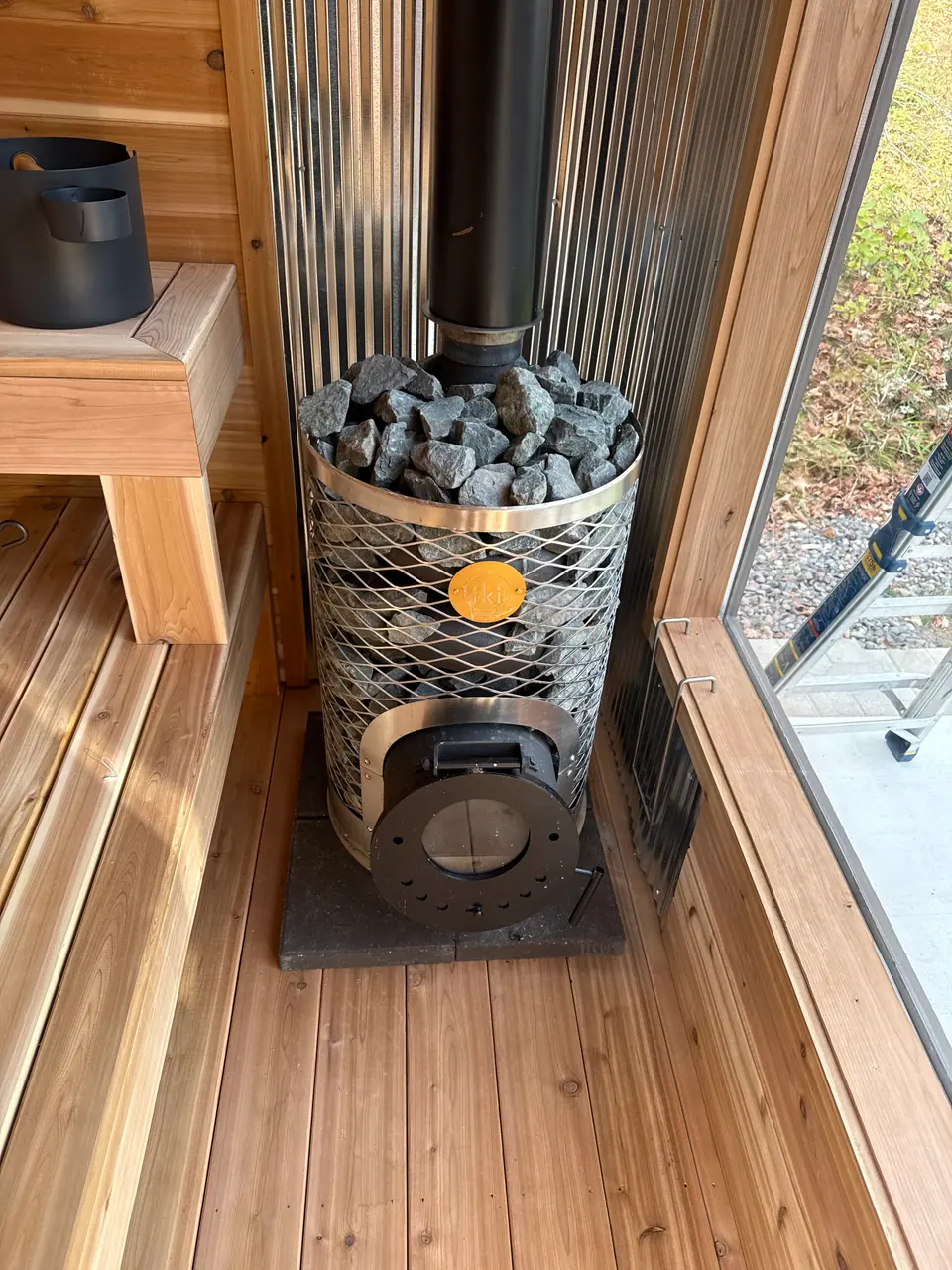 IKI Mini wood-fired stove in the corner of a cedar sauna