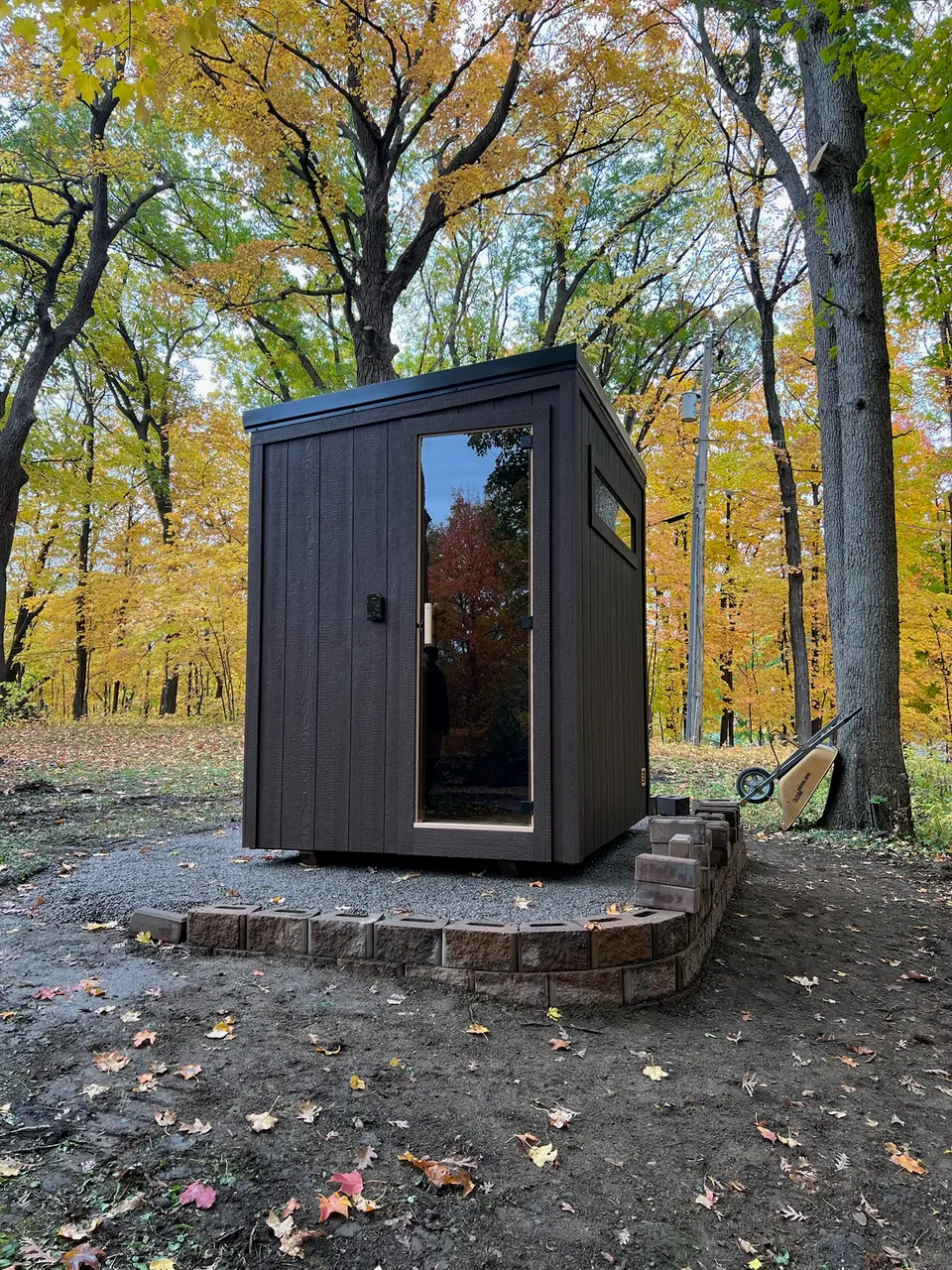 Kota sauna on a gravel pad in the woods in fall