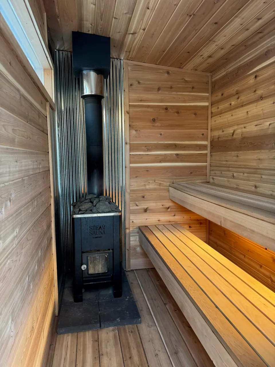Inside a Kota sauna: two tiers of cedar benches and a wood stove