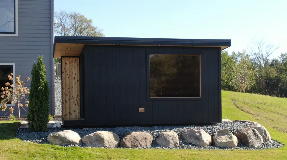 Long black Superior sauna on a lawn edged with boulders