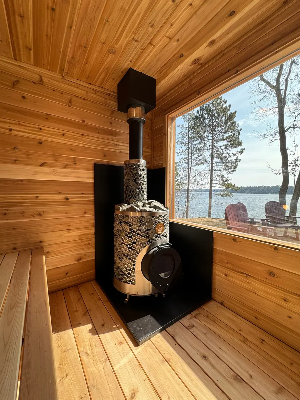 Wood stove inside a Superior sauna with a window looking out at the lake