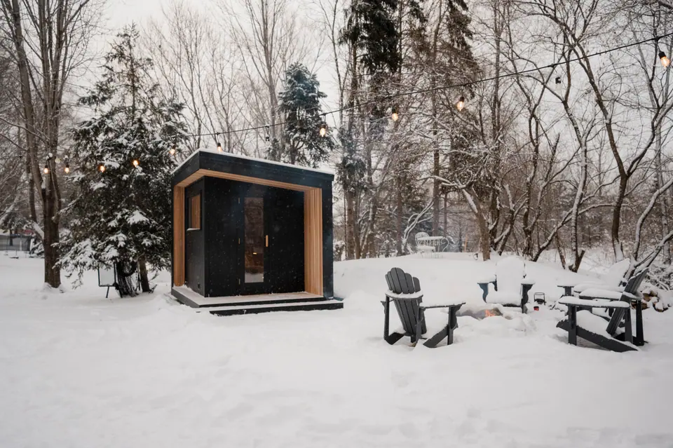 Tuli sauna at the back of a snowy yard with chairs around a fire pit