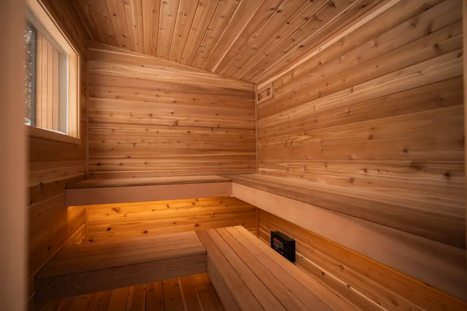 Cedar benches inside the Tuli sauna with warm light under the upper bench