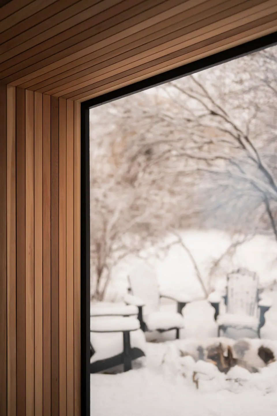 View from inside the sauna through the glass door to chairs in the snow