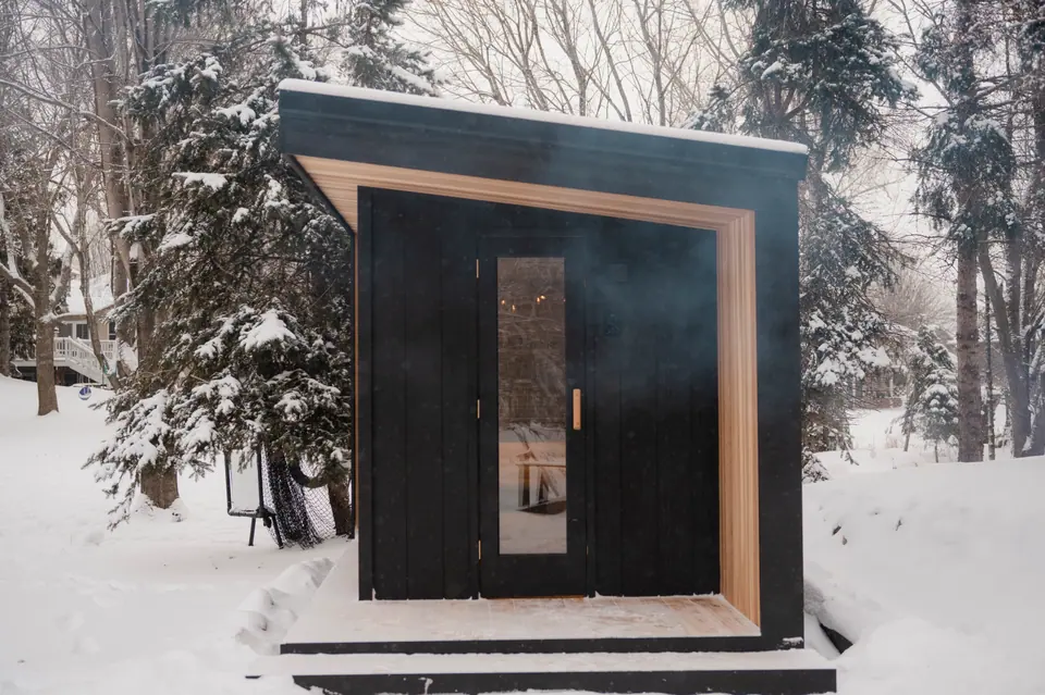 Tuli sauna in the snow with wood smoke drifting from the chimney